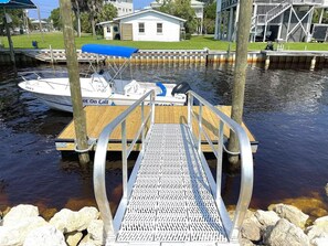 A dock with a metal walkway leading to a boat. - Walk to Mashes Sands Beach, boat from your private dock, and bask in Old Florida in this one-story canal-front home (Panacea)