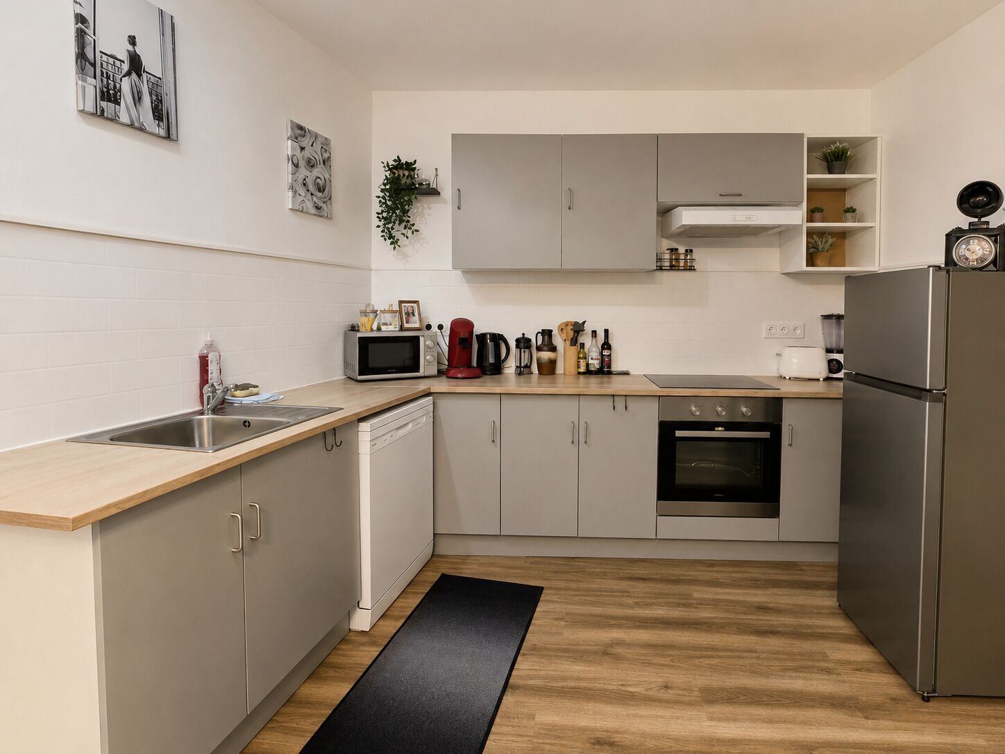 Eine moderne Küche mit einem Edelstahl-Kühlschrank, einer Mikrowelle, einem Spülbecken und einem Herd.