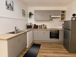 A modern kitchen with a stainless steel refrigerator, a microwave, a sink, and a stove. - THE SPACIOUS Apartment for 8–10 People in the Heart of Blois (Blois)