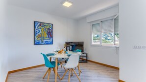 Ein Essbereich mit einem Tisch für zwei Personen, einem Bild an der Wand und einem Fenster mit Jalousien.