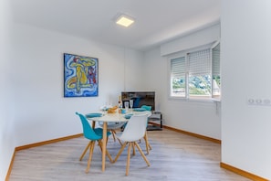 Ein Essbereich mit einem Tisch für zwei Personen, einem Bild an der Wand und einem Fenster mit Jalousien.