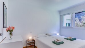 Ein Schlafzimmer mit Bett, Nachttisch und einem Fenster mit Blick auf Grünflächen.