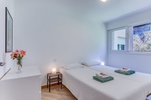 Ein Schlafzimmer mit Bett, Nachttisch und einem Fenster mit Blick auf Grünflächen.