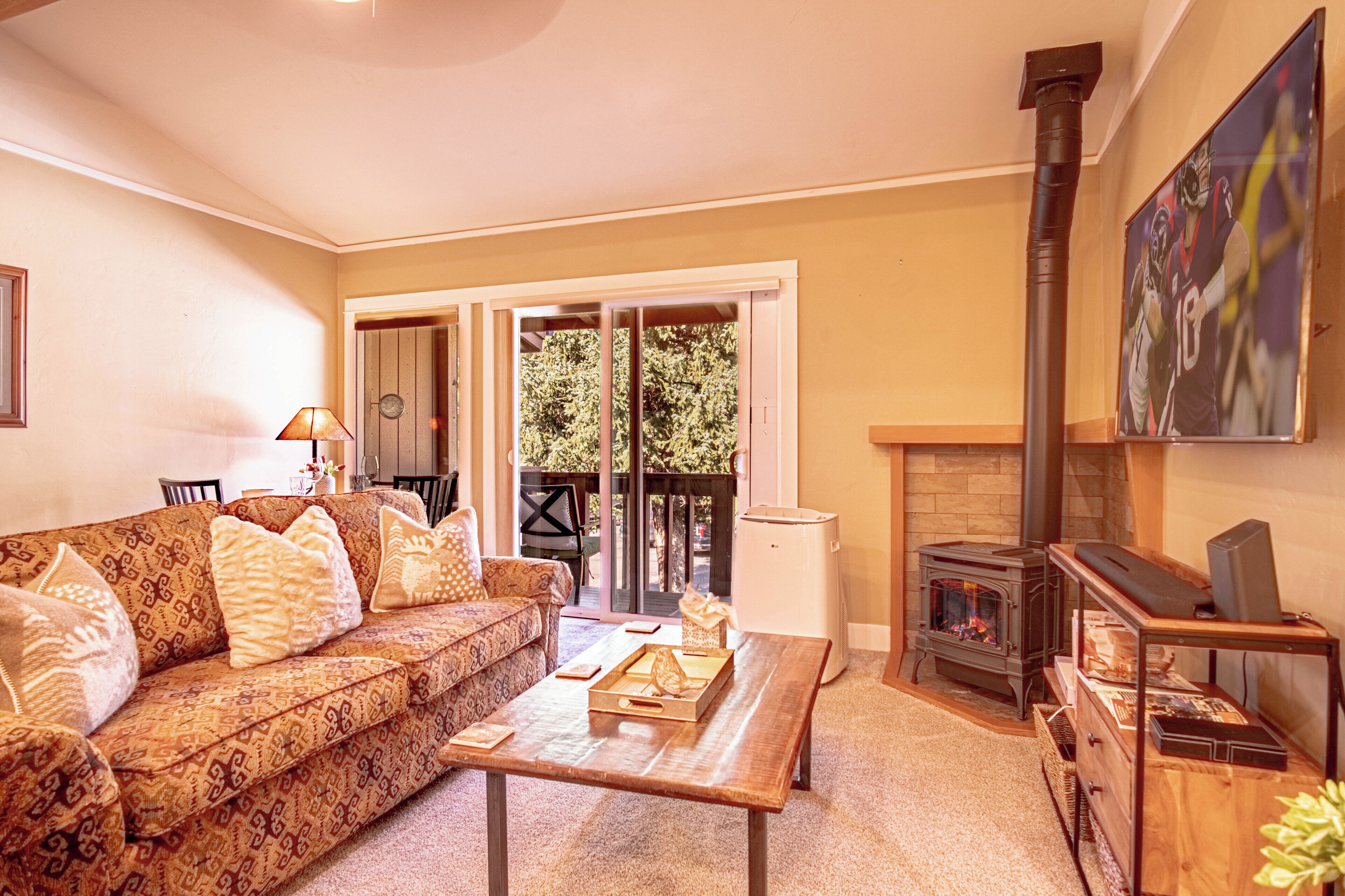 A cozy living room with a sofa, coffee table, fireplace, and a painting on the wall.