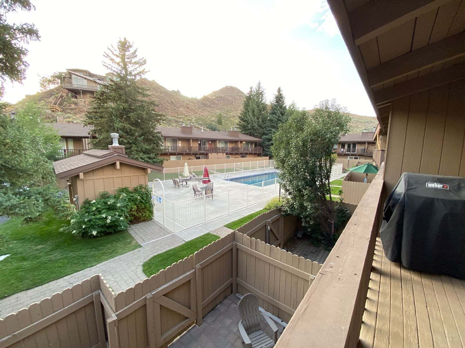 Vista de un patio trasero con piscina, mobiliario de patio y una parrilla.