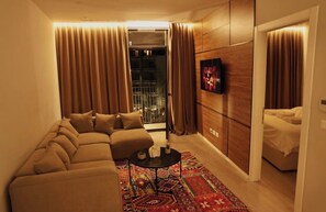 A modern living room with a sofa, a coffee table, and a TV mounted on the wall. - Lake View Reaidenc (Tiranë)