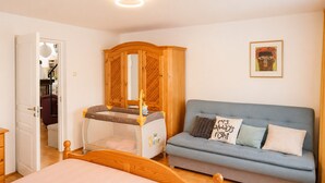 A bedroom with a bed, a wooden wardrobe, a sofa, and a crib. - Holiday Home for 8 People Mrzezyno (Trzebiatow)