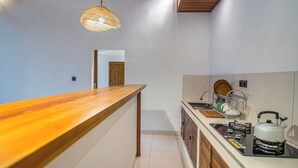 Une cuisine avec un plan de travail en bois, une bouilloire et un égouttoir à vaisselle.