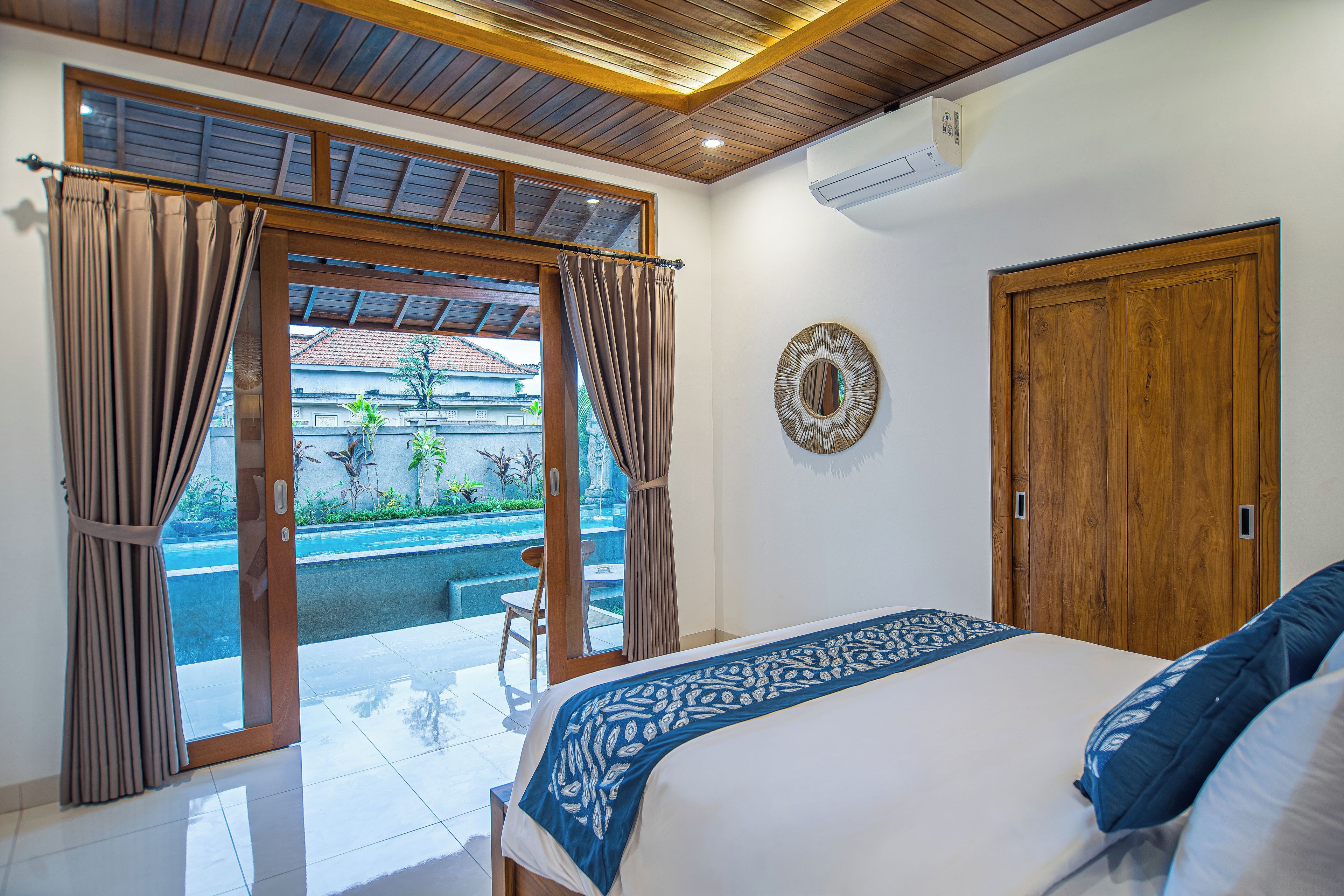 Un dormitorio con cama, puerta de madera y vista a una piscina.