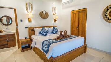 Habitación de hotel con cama y armario de madera, baño con lavamanos y espejo.