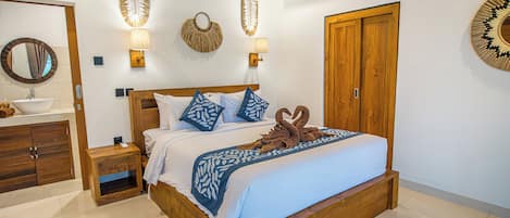 Habitación de hotel con cama y armario de madera, baño con lavamanos y espejo.