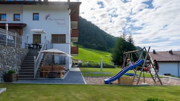 A building with a children's play area, including a slide, and a staircase leading to an outdoor seating area.