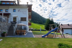 Un edificio con un'area giochi per bambini, comprensiva di uno scivolo, e una scala che conduce a una zona salotto esterna.