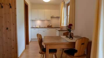 A compact kitchen with white cabinets, a wooden dining table, and chairs.