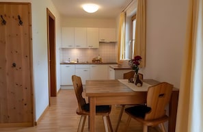 Una cucina compatta con mobili bianchi, un tavolo da pranzo in legno e sedie.