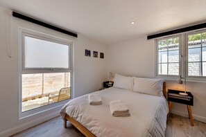 A bedroom with a bed, two bedside tables, a nightstand, and a window with a view of an outdoor area. - Host & Stay | Studio 58 (Brighton and Hove)