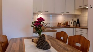 Eine moderne Küche mit weißen Schränken, einem Holztisch und einer Blumenvase.