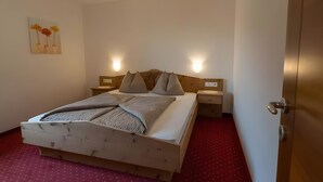 Ein ordentlich bezogenes Bett mit Kopfteil, zwei Nachttischen und einer wandmontierten Leuchte.