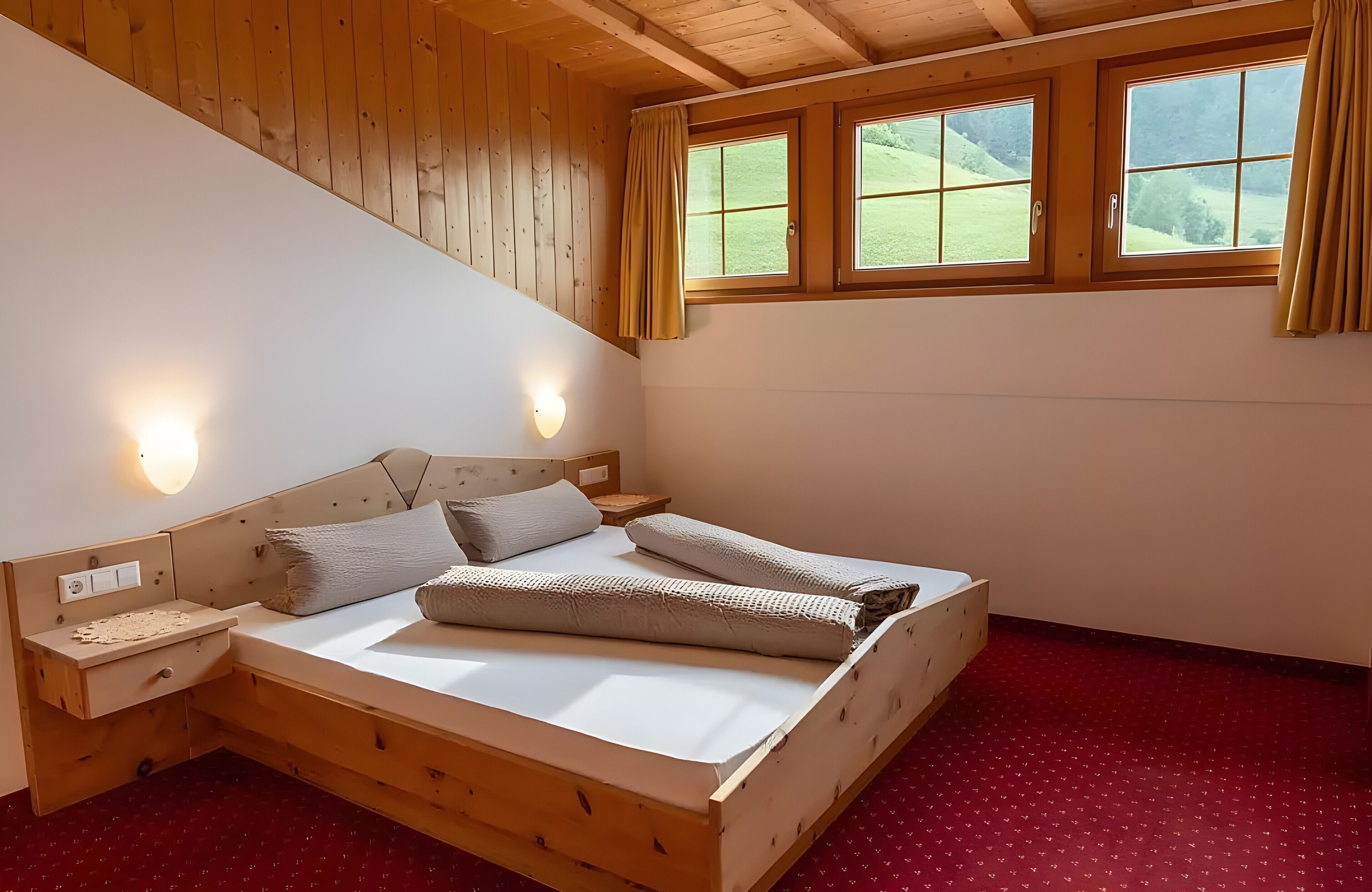 Un lit en bois avec une tête de lit, deux tables de chevet et une fenêtre avec des rideaux.
