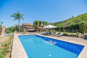 A rectangular swimming pool with clear blue water, surrounded by lounge chairs and a stone wall. - Historic Villa With Mountain Views, Mallorca (Pollença)