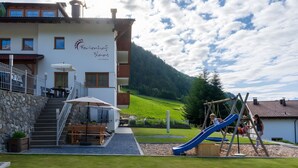 Ein Gebäude mit Kinderspielbereich, darunter eine Rutsche, und einer Treppe zu einer Außen-Sitzgelegenheit.