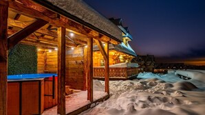 A wooden cabin with a covered outdoor area, snow accumulation, and a view of a mountain range at dusk. - Two-story Mountain-style House, Sauna, Jacuzzi (Poronin)