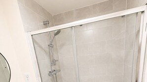 Un bagno moderno con cabina doccia in vetro, un lavandino bianco e uno specchio.
