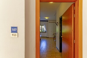 A hallway with a number sign, a door, and a window. - A cozy studio apartment with a balcony and kitchenette—perfect for two—located within the Campoverde Residence in Vernole, set in a Mediterranean pine forest between San Cataldo and the Le Cesine Nature Reserve. The property is just a short distance  (Vernole)