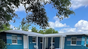 En blå bygning med to etager, en overdækket terrasse og et picnicbord.