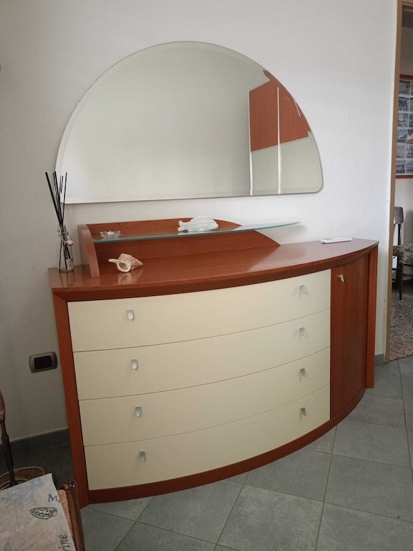 Un baño con tocador de madera, un espejo grande y piso de baldosas.