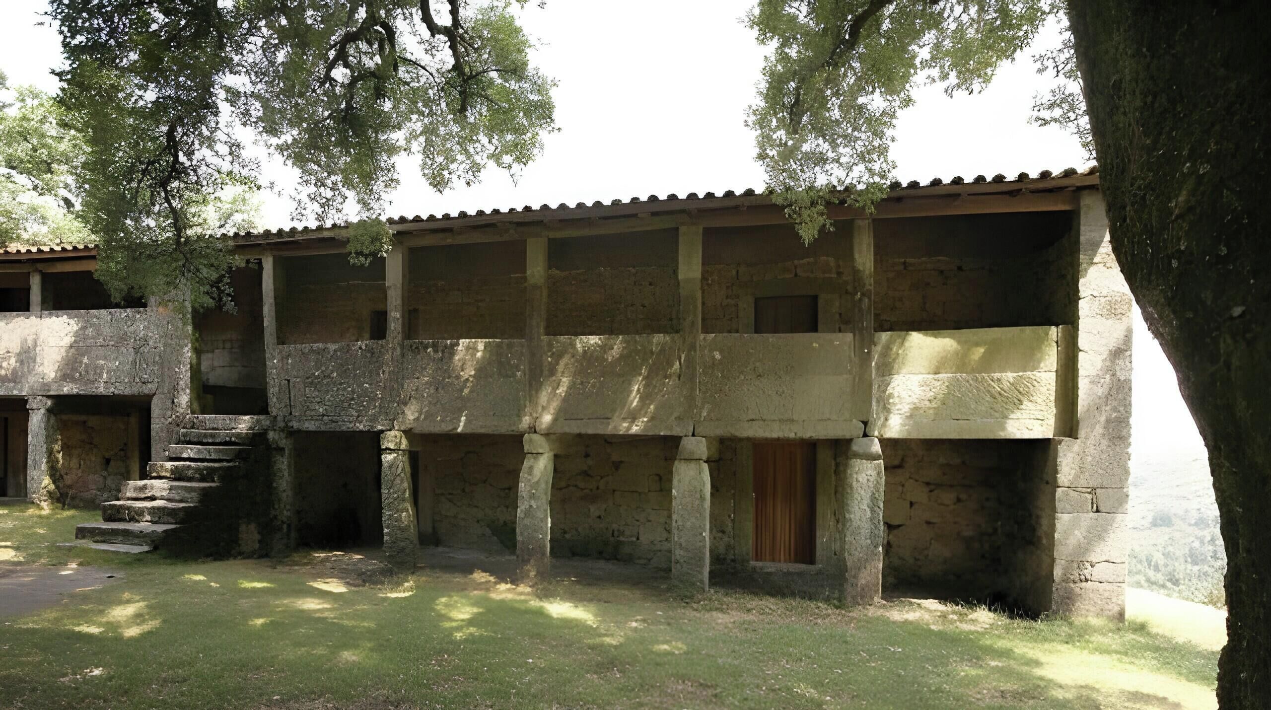 Un edificio con fachada de piedra, múltiples ventanas y una escalera que conduce a un nivel superior.