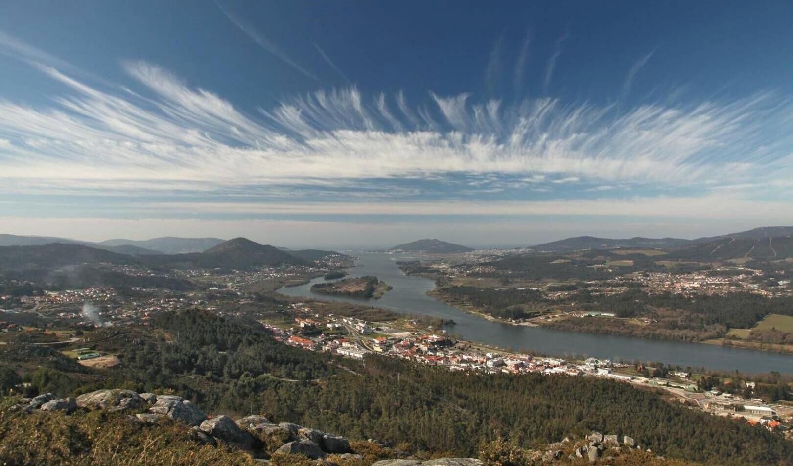 Vista panorámica de un pueblo junto a un río, con montañas al fondo.
