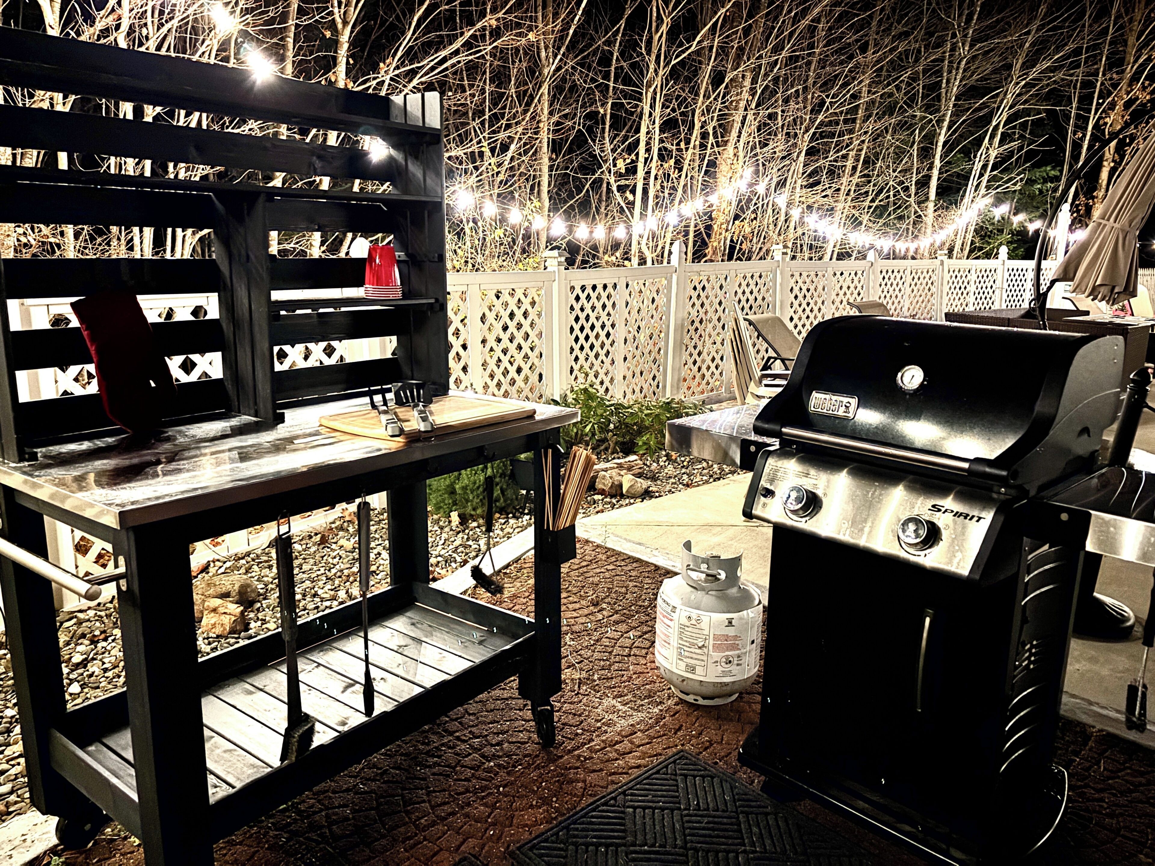 An outdoor barbecue setup with a grill and a table with utensils.