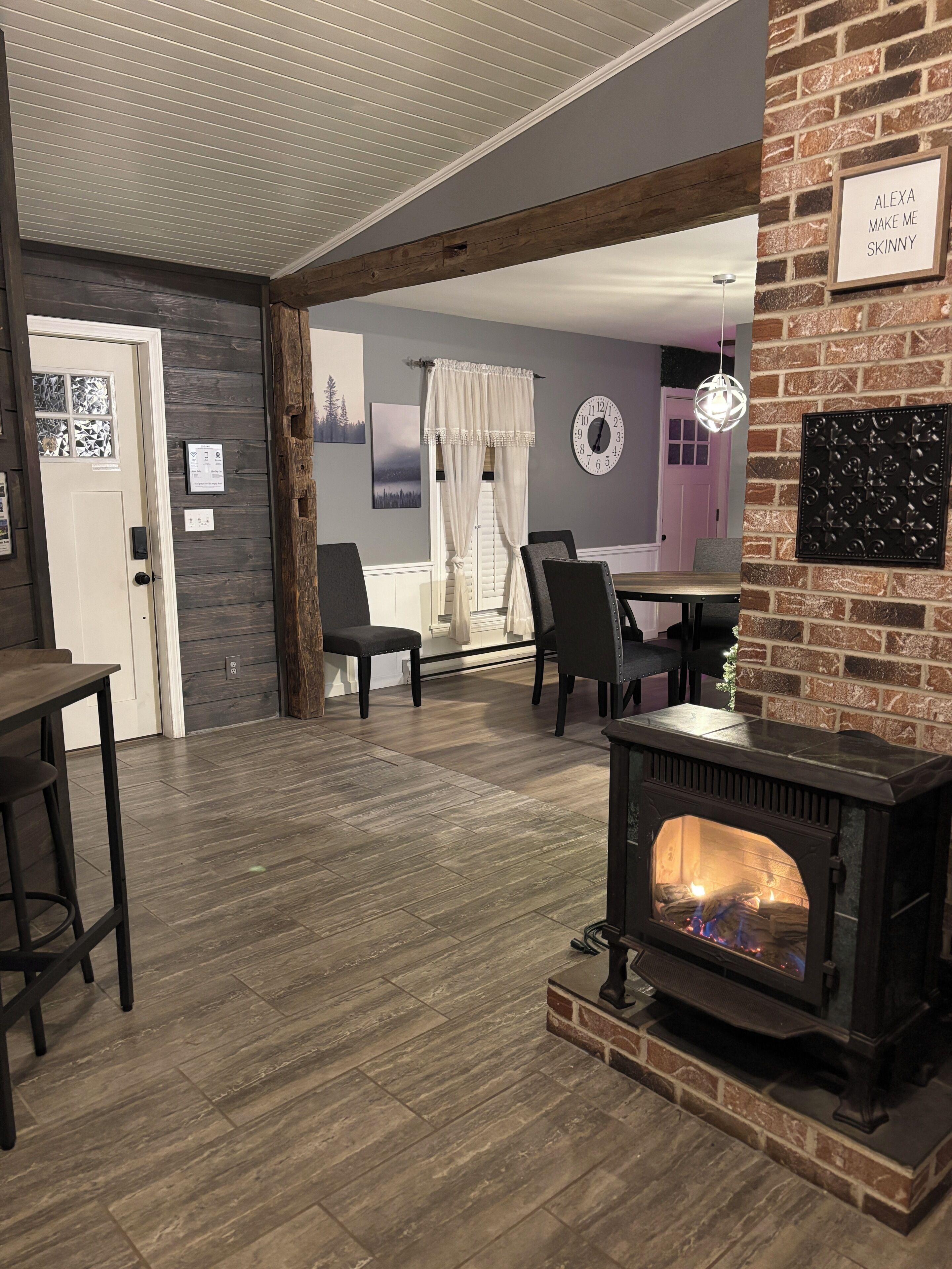 A cozy living room with a fireplace, wooden flooring, and a dining area with chairs and a table.