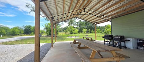 A covered outdoor area with picnic tables and barbecue grills.