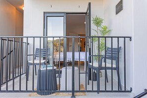 A balcony with a metal railing, two chairs, a small round table, and a potted plant. - FYNBOS - Stylish, Fully equipped Simon's Town apartment, 400m from the beach (Cape Town)