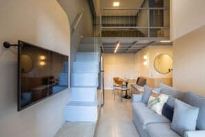 A modern interior with a staircase, a dining area, and a seating area with a sofa and a mirror. - Highlights Pinheiros (São Paulo)