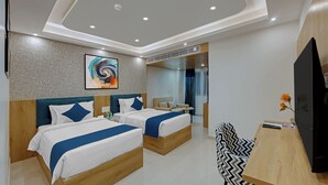Habitación de hotel con dos camas, un escritorio, un televisor y un cuadro en la pared.
