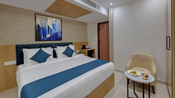 Una moderna camera d'albergo con un letto grande, un tavolino con della frutta, una sedia e un quadro appeso al muro.