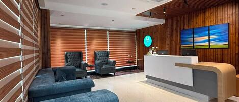 A modern reception area with a wooden wall, a reception desk, and a large landscape painting.