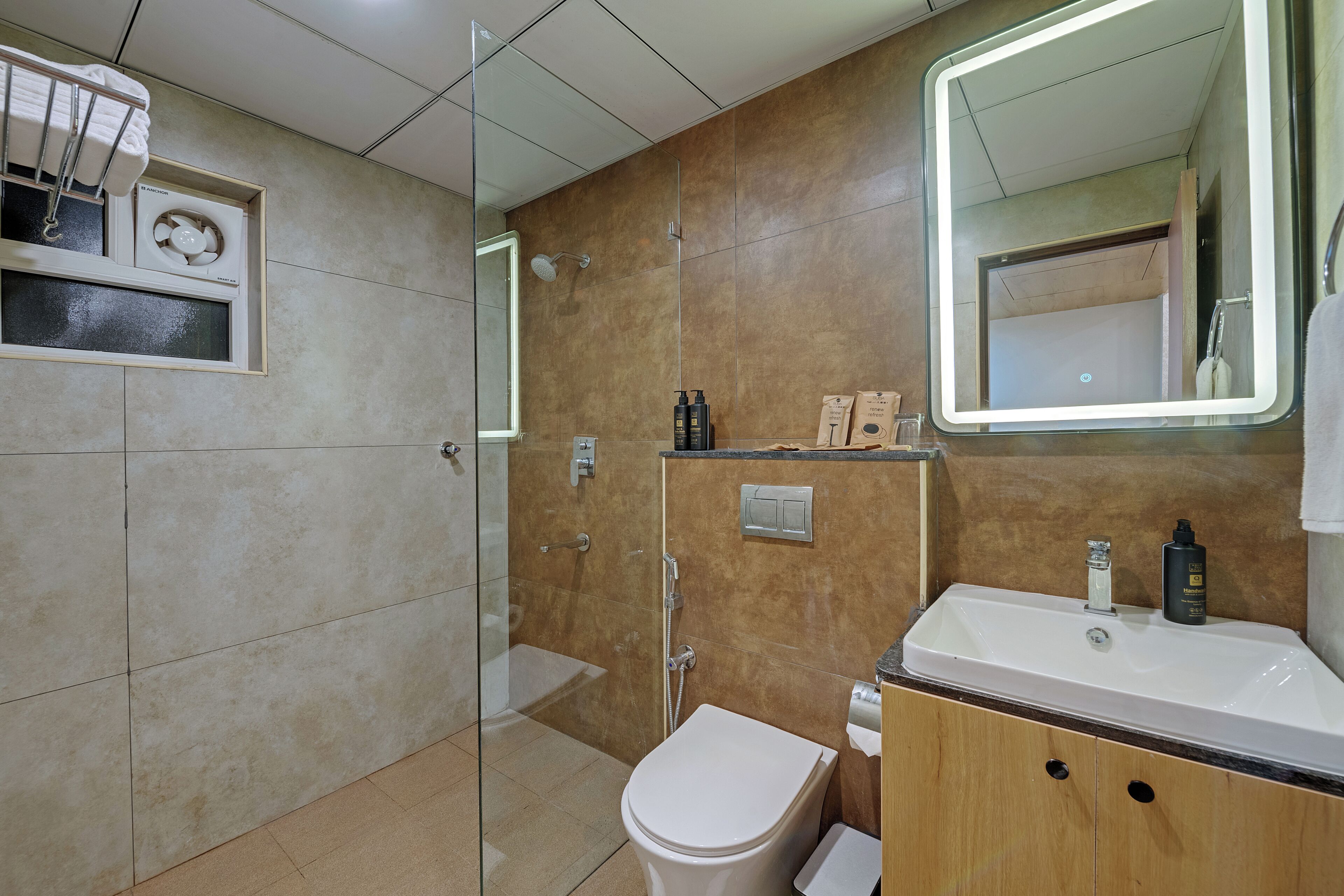 Un baño moderno con cabina de ducha de vidrio, un inodoro blanco y un lavabo con espejo.