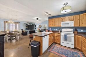 A spacious kitchen with wooden cabinets, a microwave, an oven, and a dining area with a table and chairs. - New listing! 4-BR Moab Retreat | Pool | Hot tub | Fenced yard with BBQ (Moab)