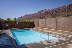 A rectangular swimming pool with a metal ladder, surrounded by a concrete deck. - New listing! 4-BR Moab Retreat | Pool | Hot tub | Fenced yard with BBQ (Moab)