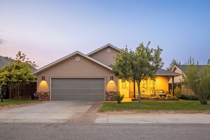 Una casa residencial con garaje, césped cuidado y un porche con mobiliario exterior.
