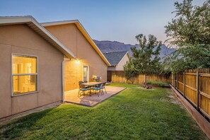 Un patio trasero residencial con una terraza, una parrilla y una valla de madera.