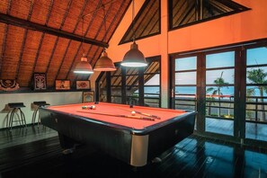 A pool table with cues and balls, a bar area with stools, and large windows with a view of the sea. - Bali luxery beach villa near lovina (Banjar)