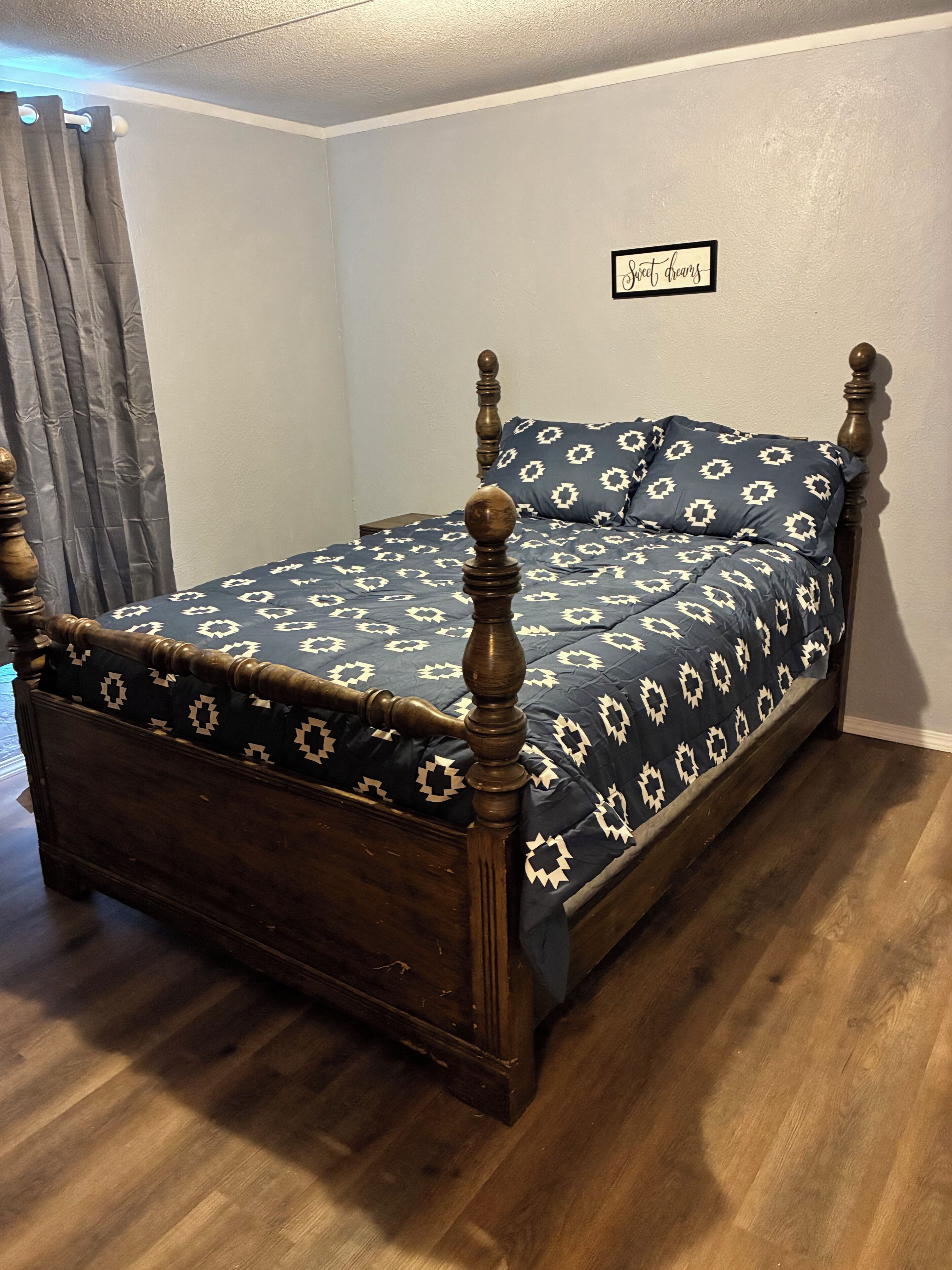 Una cama individual con estructura de madera y colcha estampada.