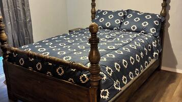 Una cama individual con estructura de madera y colcha estampada.