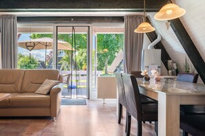 Un soggiorno moderno con divano, tavolo da pranzo, sedie e vista sull'esterno tramite ampie vetrate.