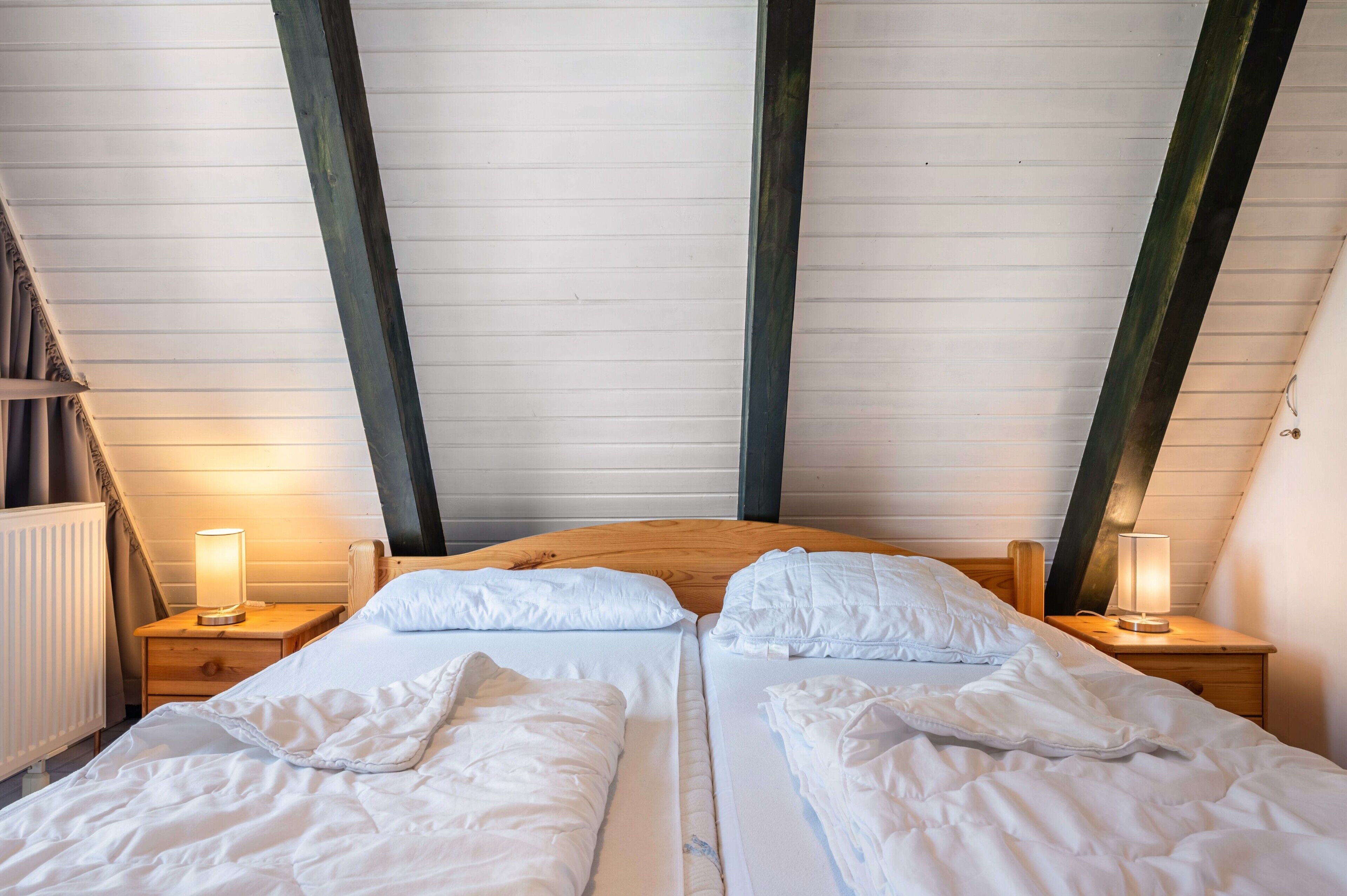 A bedroom with two beds, wooden headboards, and bedside lamps.